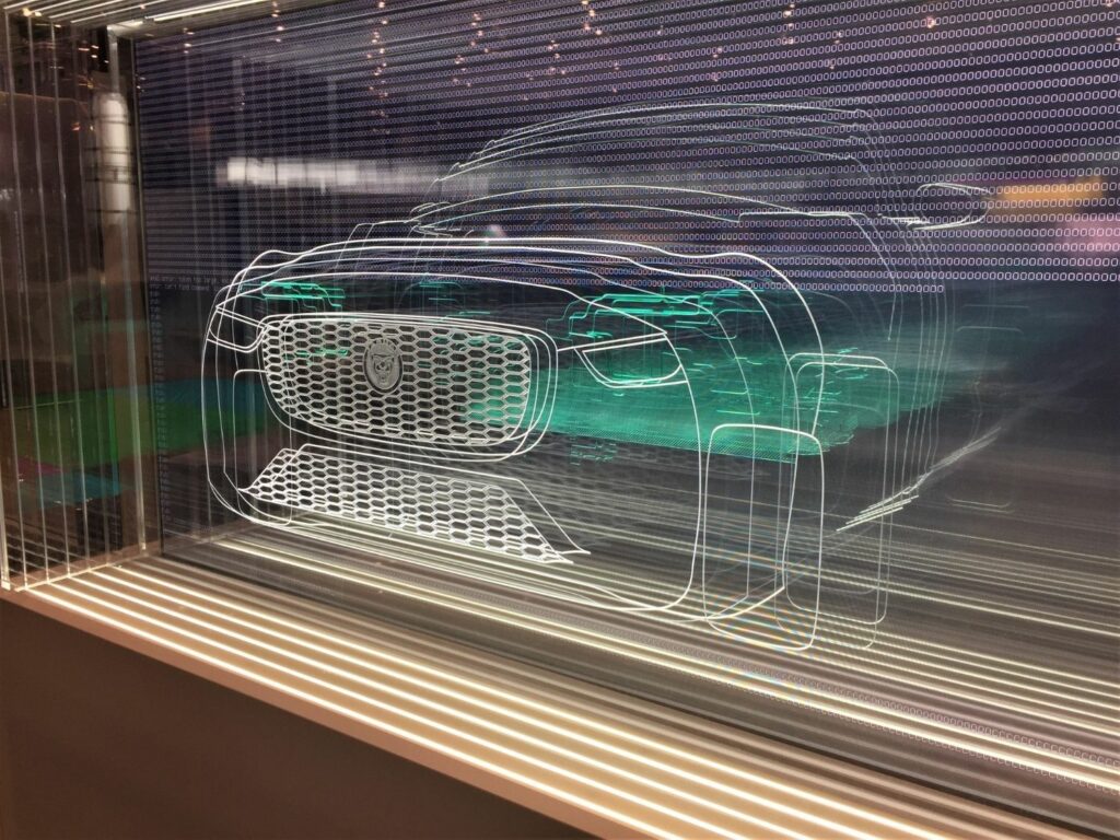 Sheets of clear acrylic with different cross sections of a jaguar engraved into each panel. All the individual panels are lined up to give a picture of the whole car.