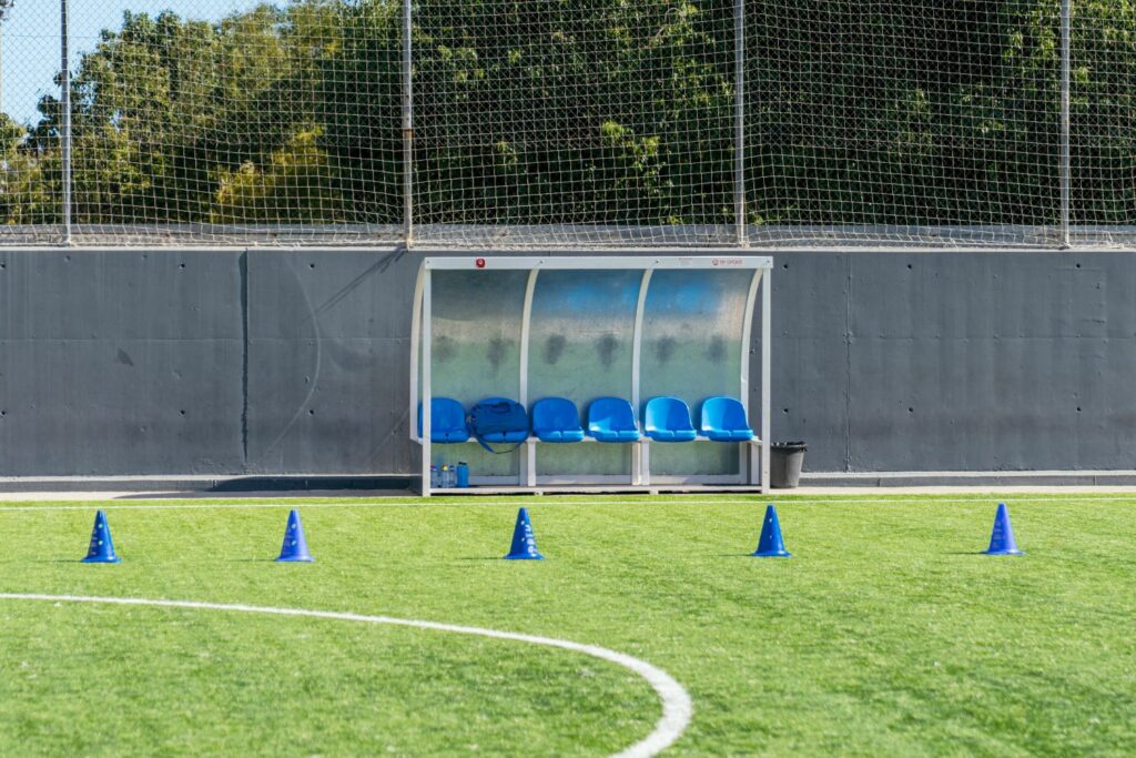 Photo of a football dug out at the side of a pitch for players to take shelter from the elements if they aren't playing.