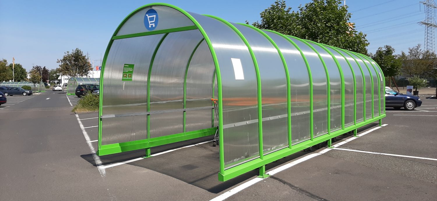 A photo of a trolley shelter with clear polycarbonate in an arch along the length of the shelter to keep the trollies dry.
