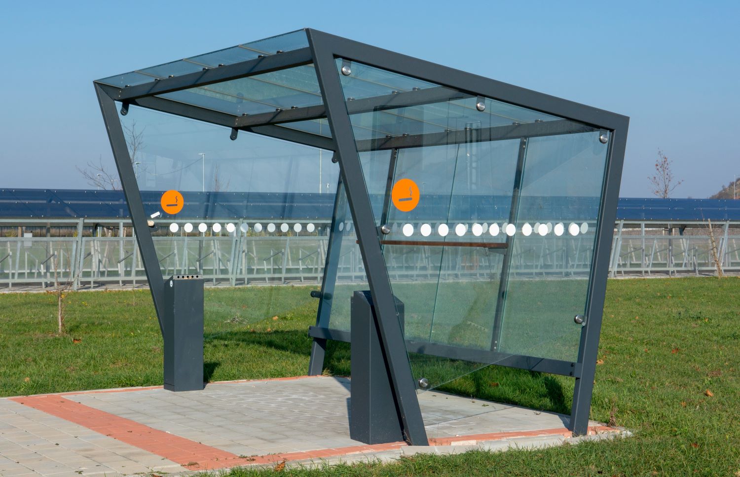 A modern looking smoking shelter with flat sheets of polycarbonate for the roof and walls.